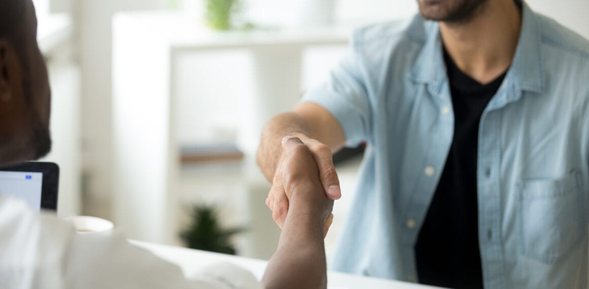 Dois homens apertando as mãos em sinal de acordo e parceria de negócios em um escritório, representando o foco no cliente da Dancor.