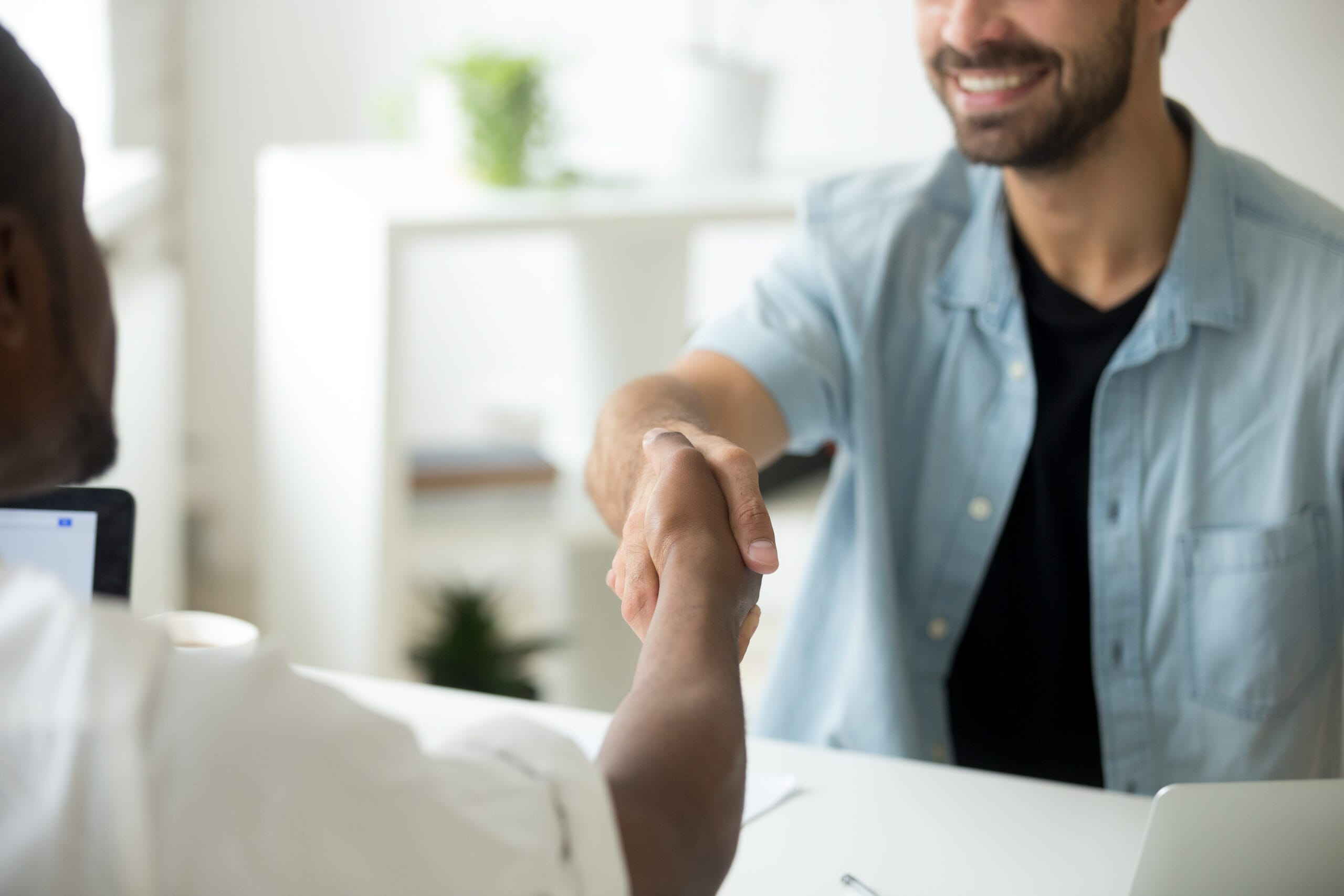 Dois homens apertando as mãos em sinal de acordo e parceria de negócios em um escritório, representando o foco no cliente da Dancor.